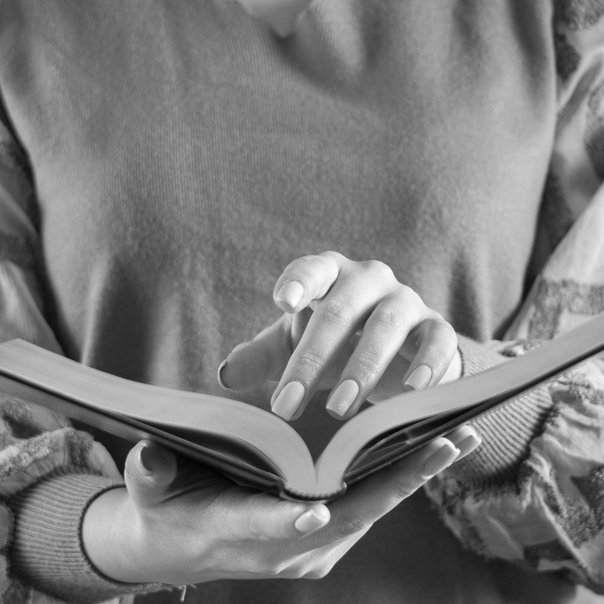 a person holds a book open as they run a finger along a page