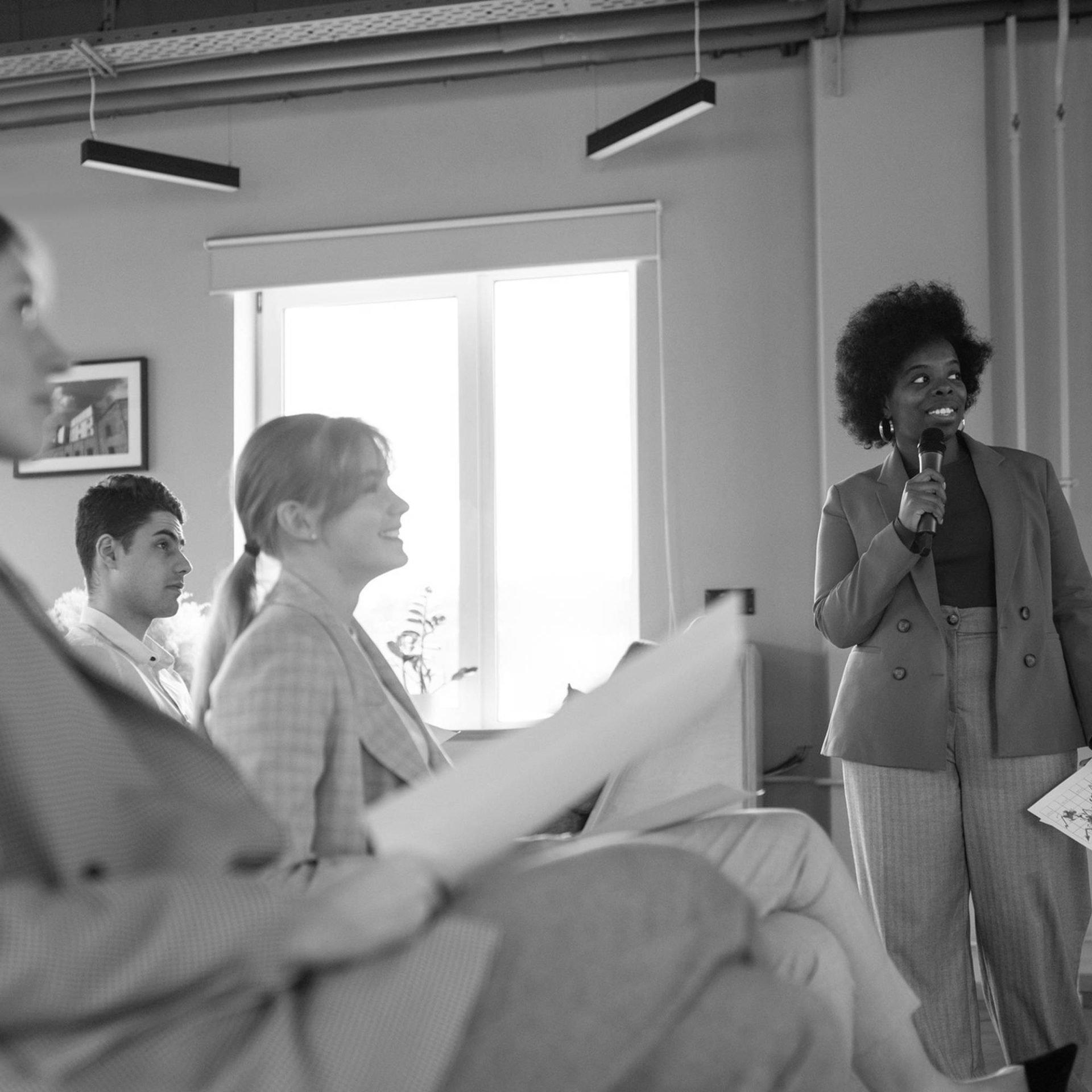 a woman stands at the front of an audience and speaks into a microphone