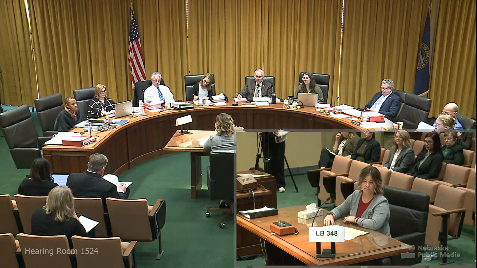 a screenshot of a Nebraska Legislative hearing where a person sits in front of a committee to testify