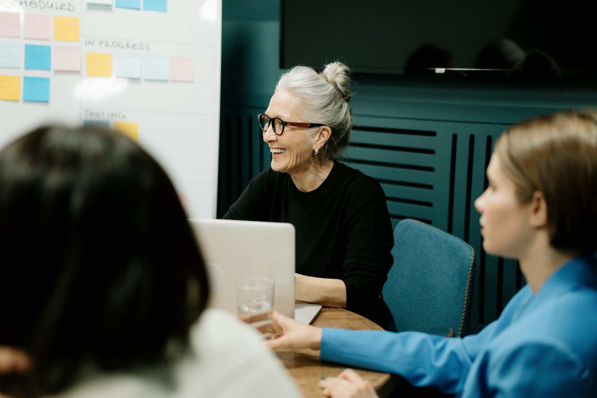 an older woman laughs as she sits in a meeting
