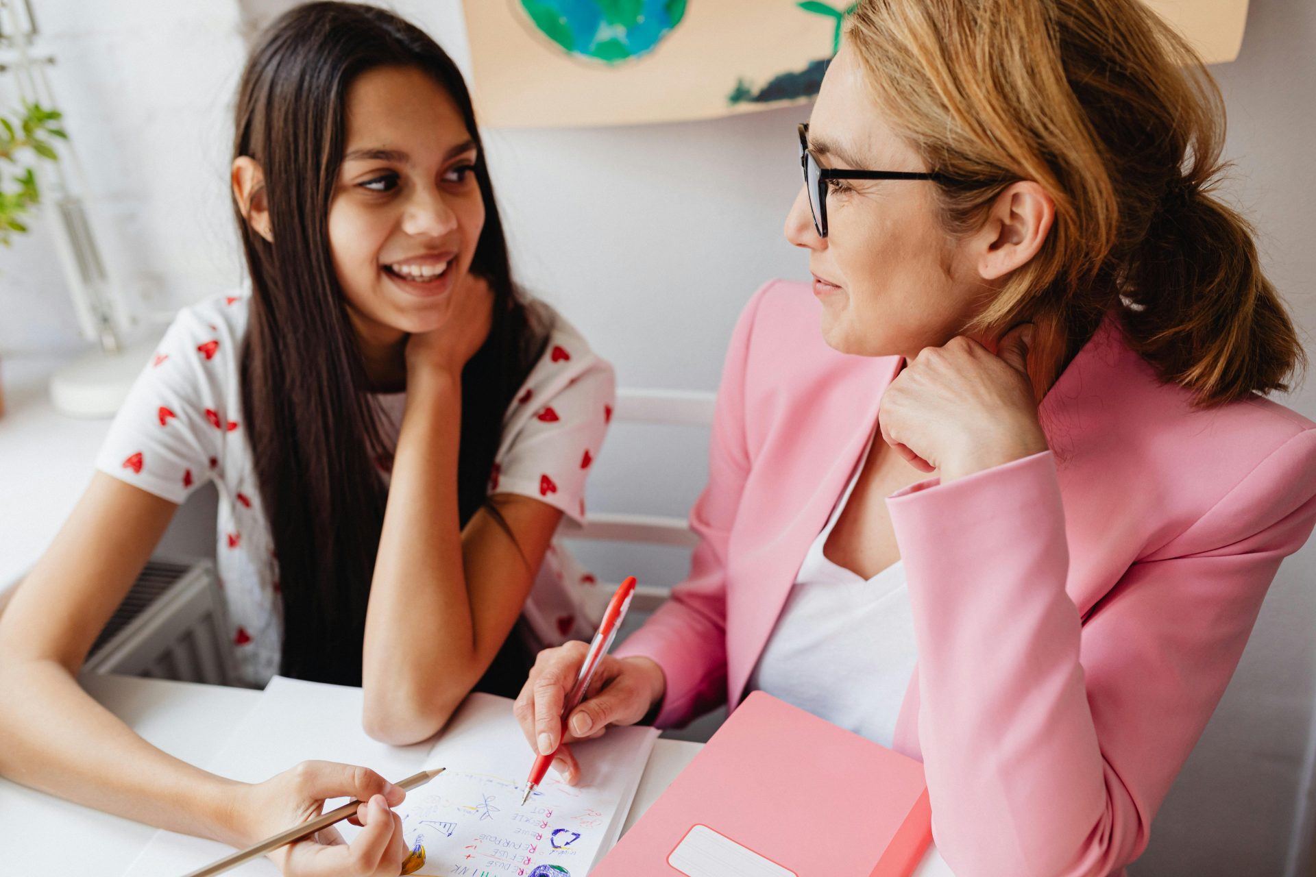an adult woman smiles as she looks to a teenage women who appears to laugh