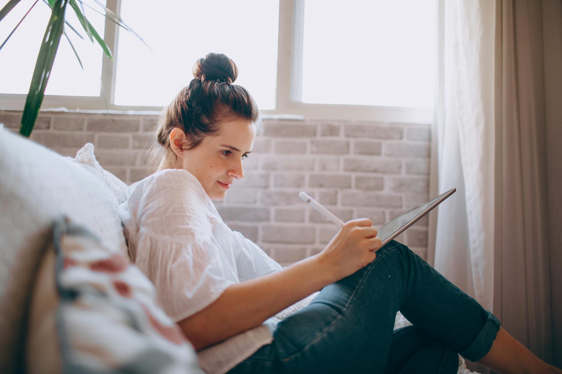woman sitting on a couch write in a notebook